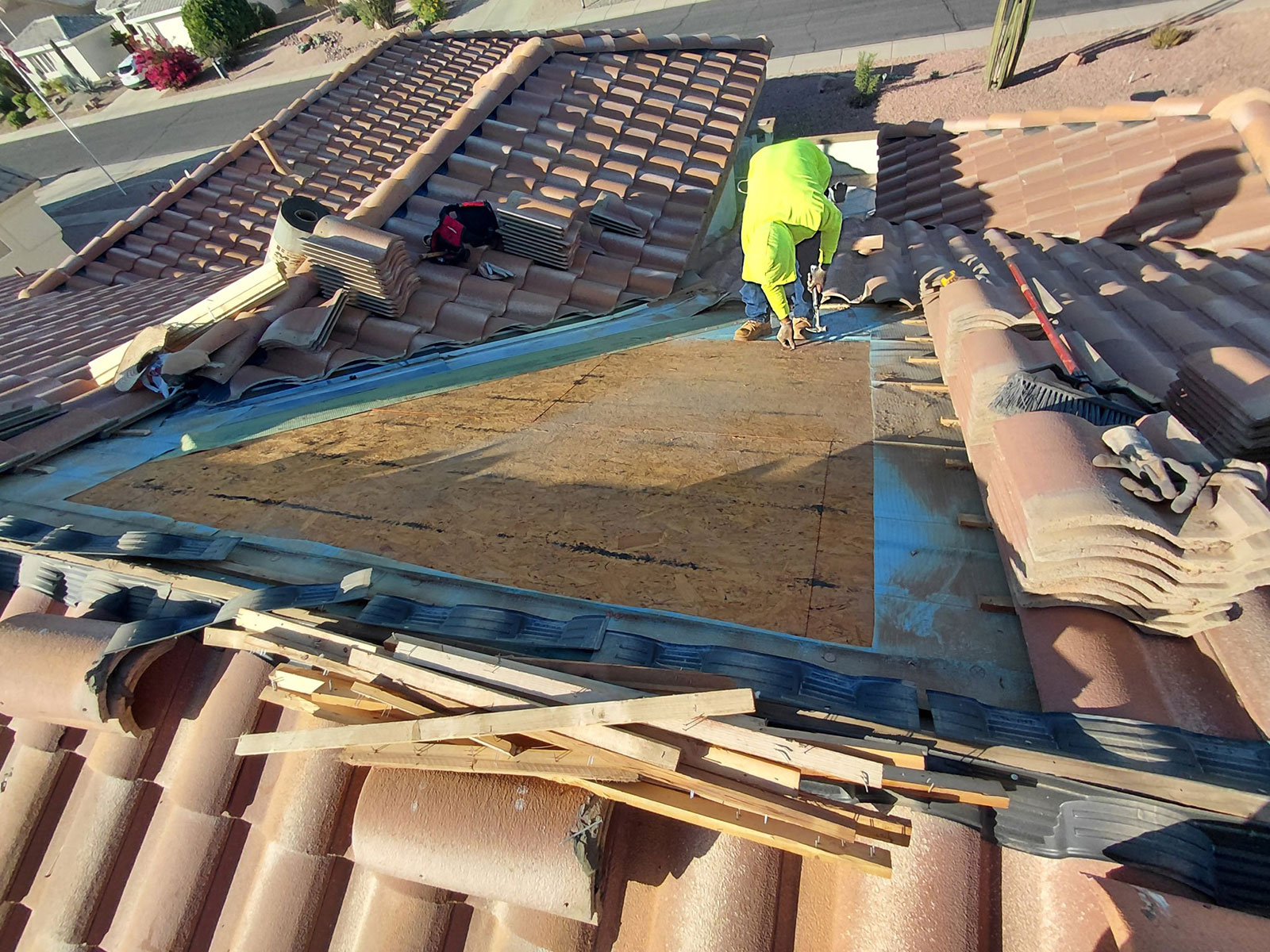 Tile roof repair in Sun City West AZ showing exposed OSB roof decking during inspection and underlayment replacement