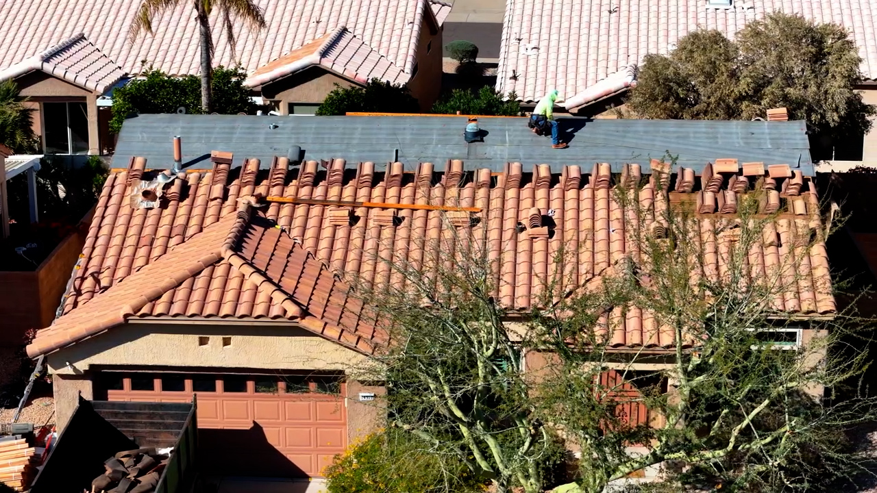 Tile roof installation in Sun City Arizona showing tiles being reinstalled during roof replacement